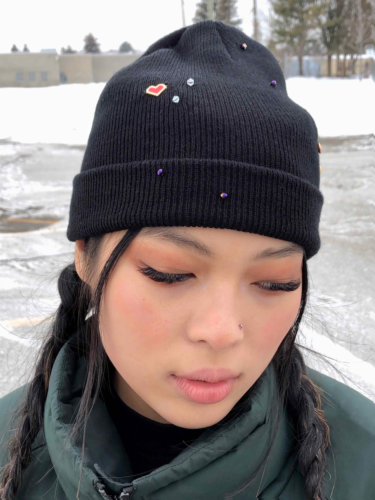 A black beanie accessorized using a heart charm and crystal beads.