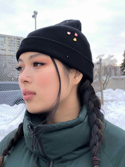 A black beanie accessorized using evil eye charms, and crystal beads. 