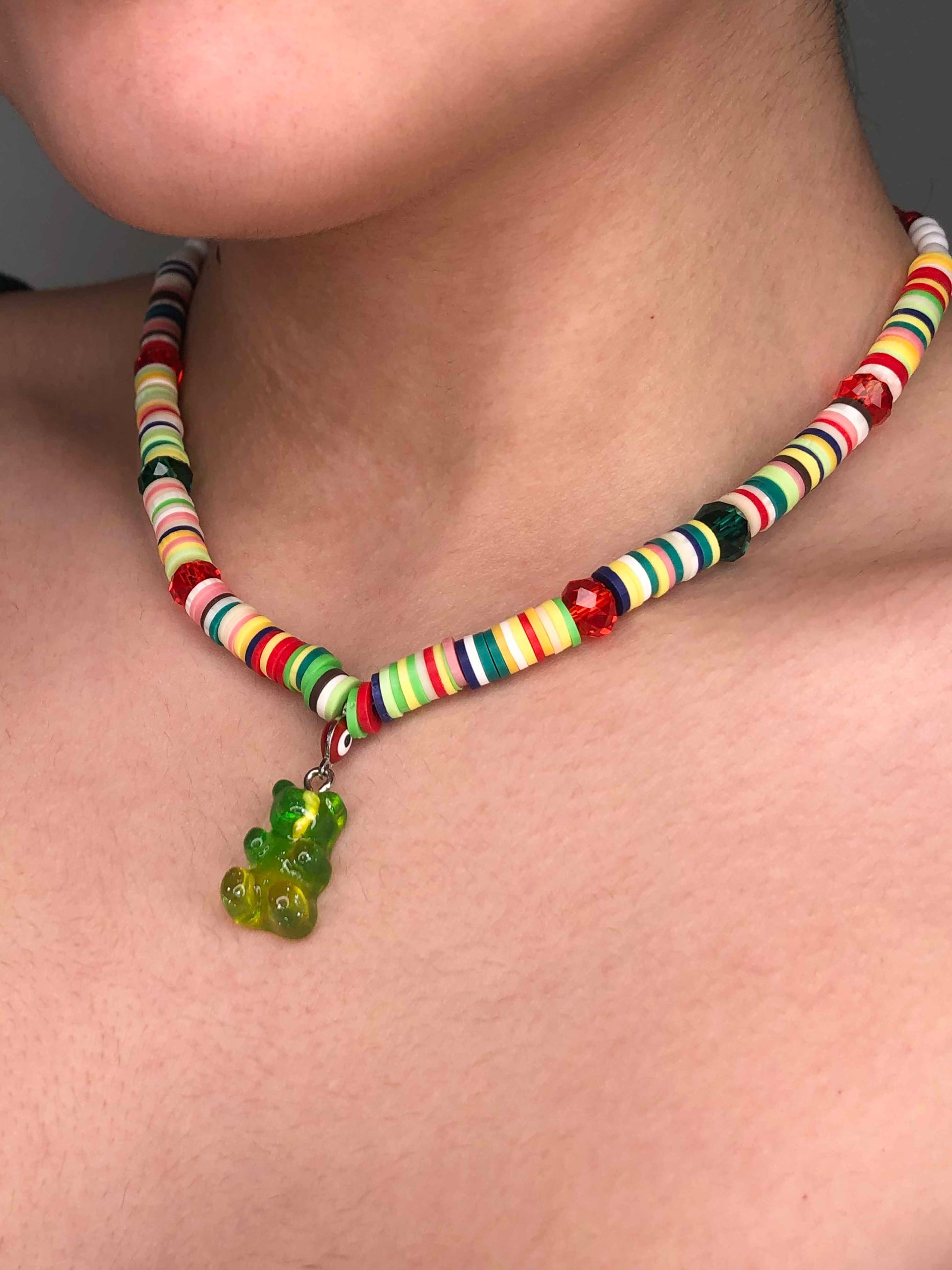 multicolored crystal and glass beaded necklace with a red evil eye, and green and yellow gummy bear-like charm