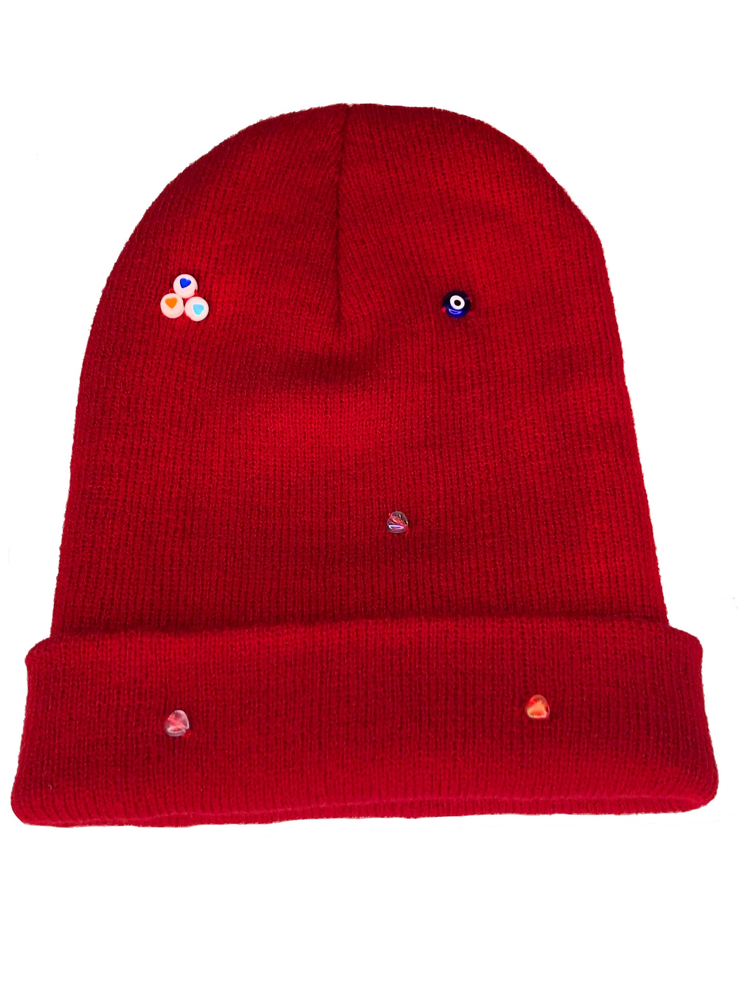 A red wool knit beanie decorated with both multicolor glass and circle heart beads, and an evil eye charm. 