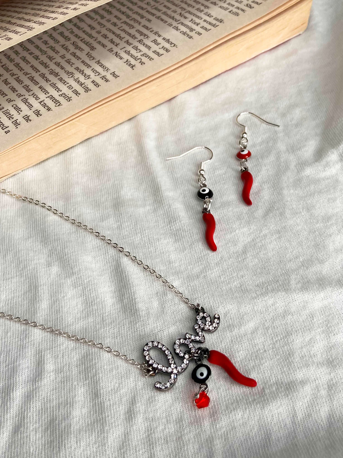 A matching set of a handmade pair of earrings and necklace made using evil eye and chili pepper charms.