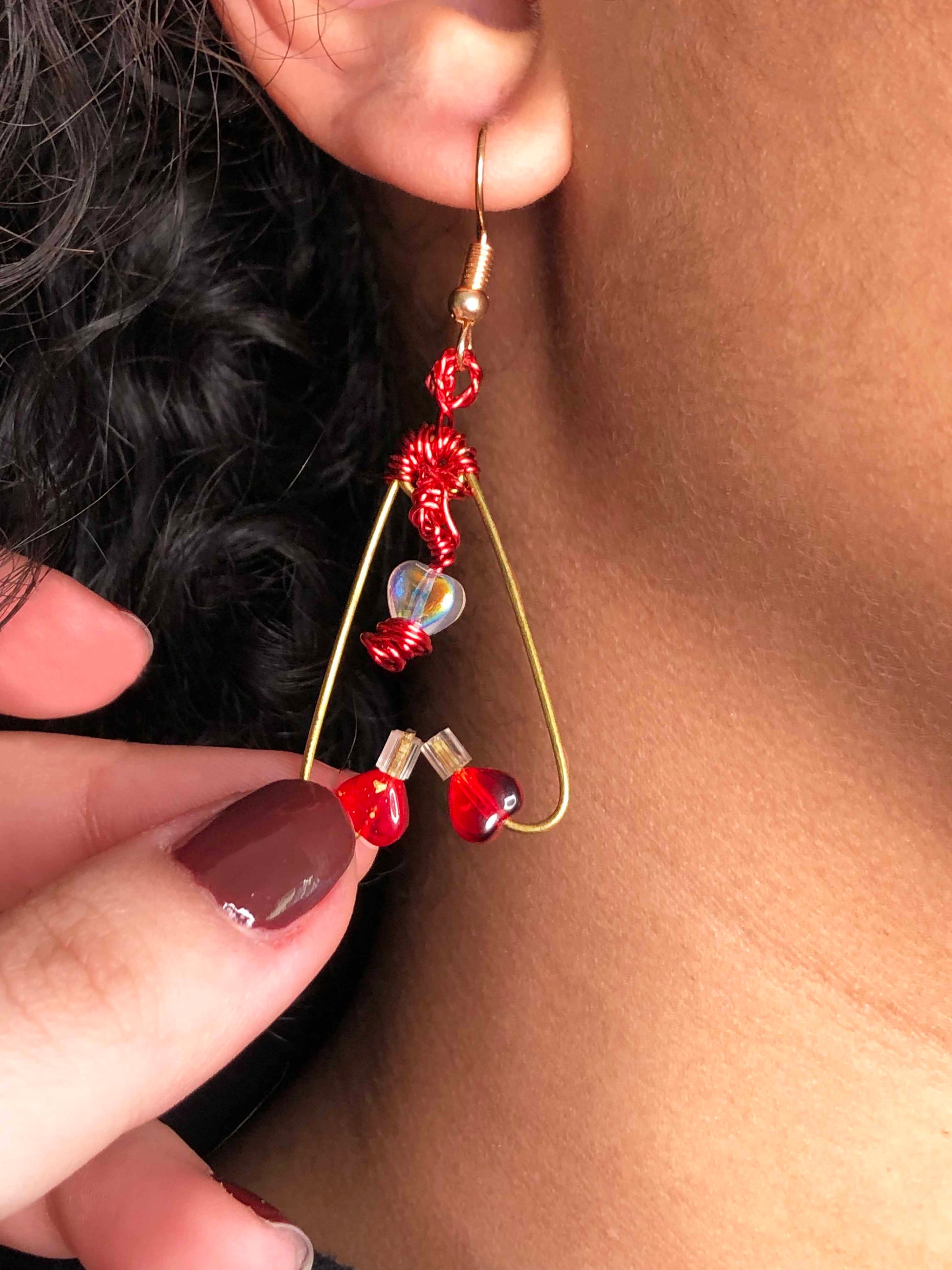 A pair of mismatched asymmetrical earrings wire wrapped using red and gold wires with clear & red heart beads, and a red crystal bead.