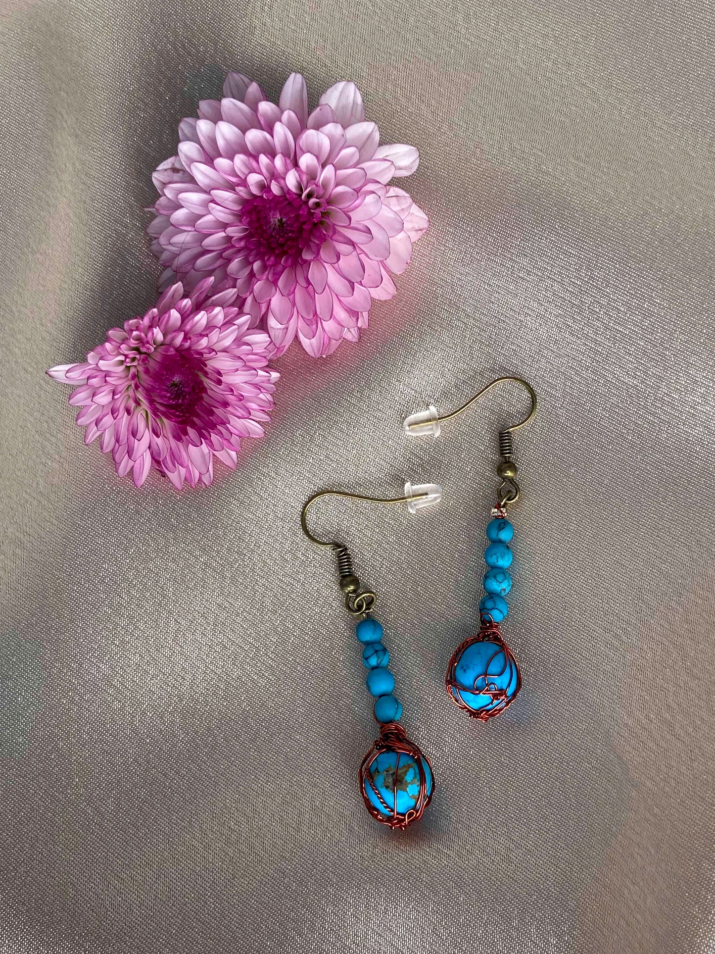 A pair of handcrafted wire-wrapped and beaded turquoise earrings.