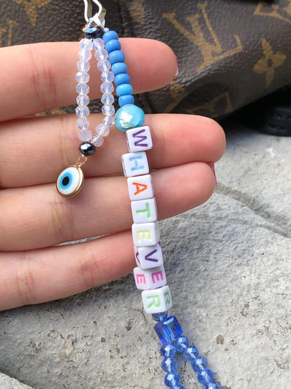 Blue and white crystal beaded bag charm with whatever spelled out using letter beads and an evil eye charm.