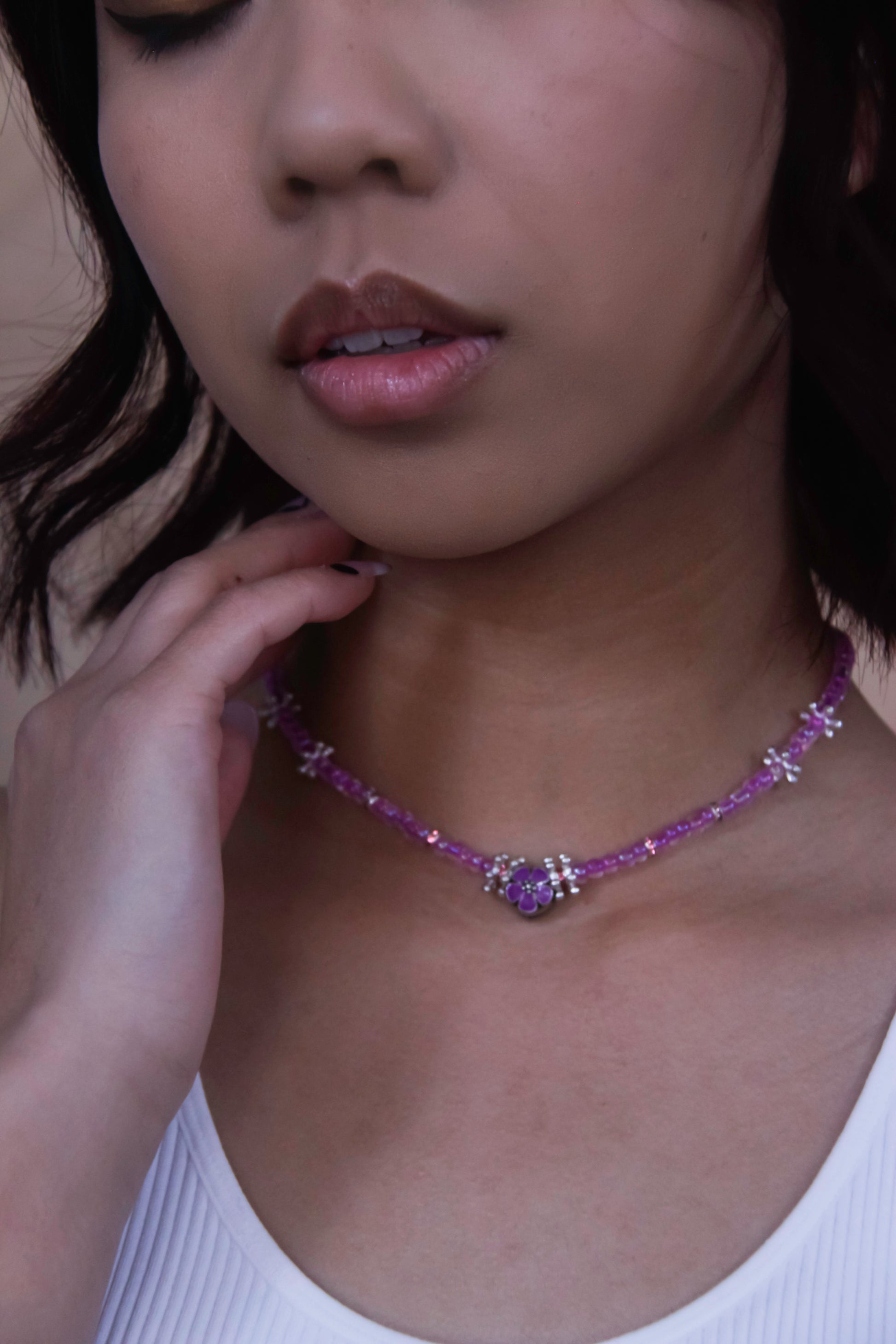 Handmade glass beaded necklace with silver flower charms, and a purple flower charm centerpiece. 