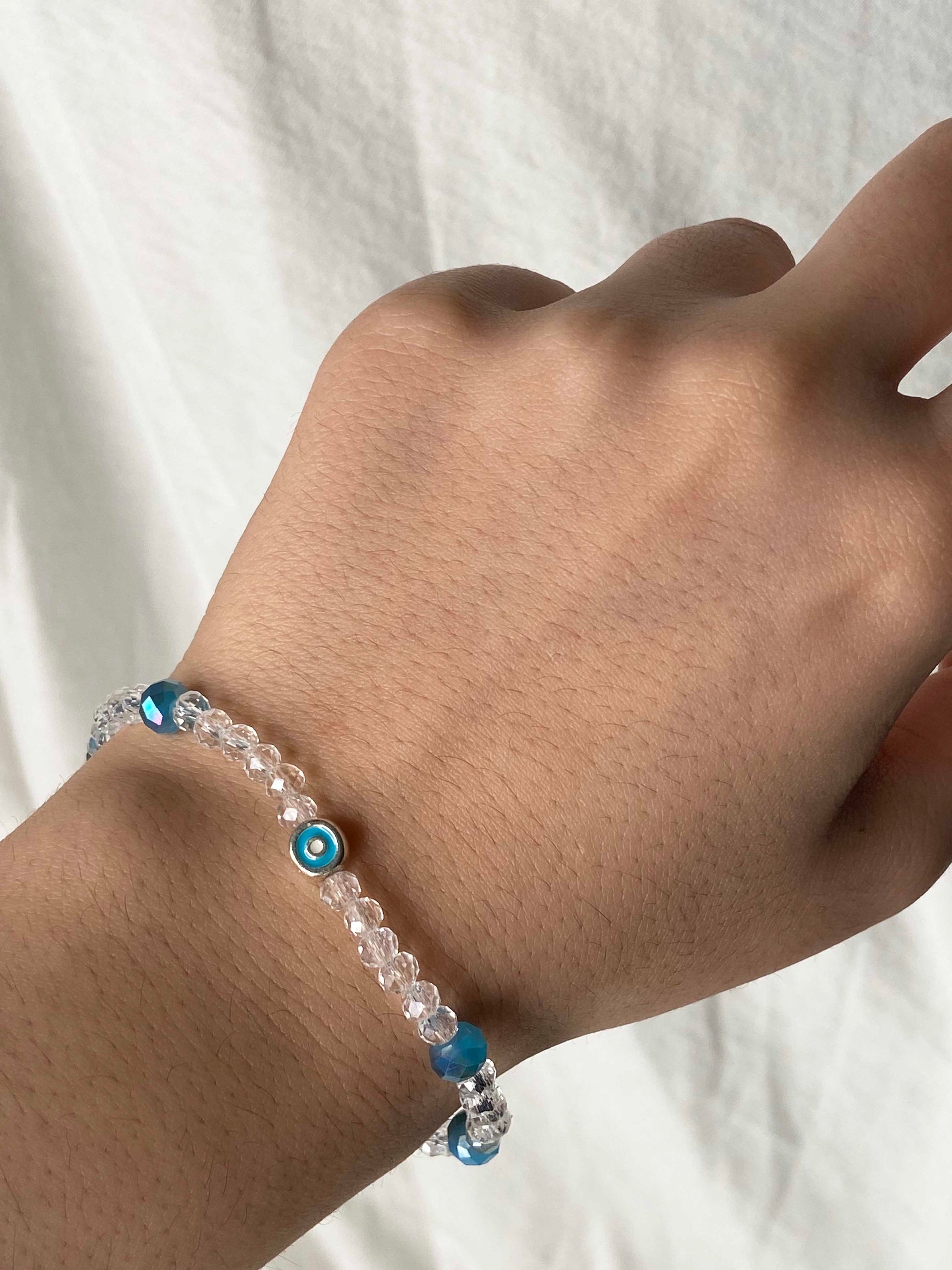 Handmade clear and blue crystal beaded bracelet with a silver backed blue evil eye charm.