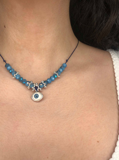 Handcrafted blue crystal and silver flower beaded necklace with silver backed evil eye charm. 