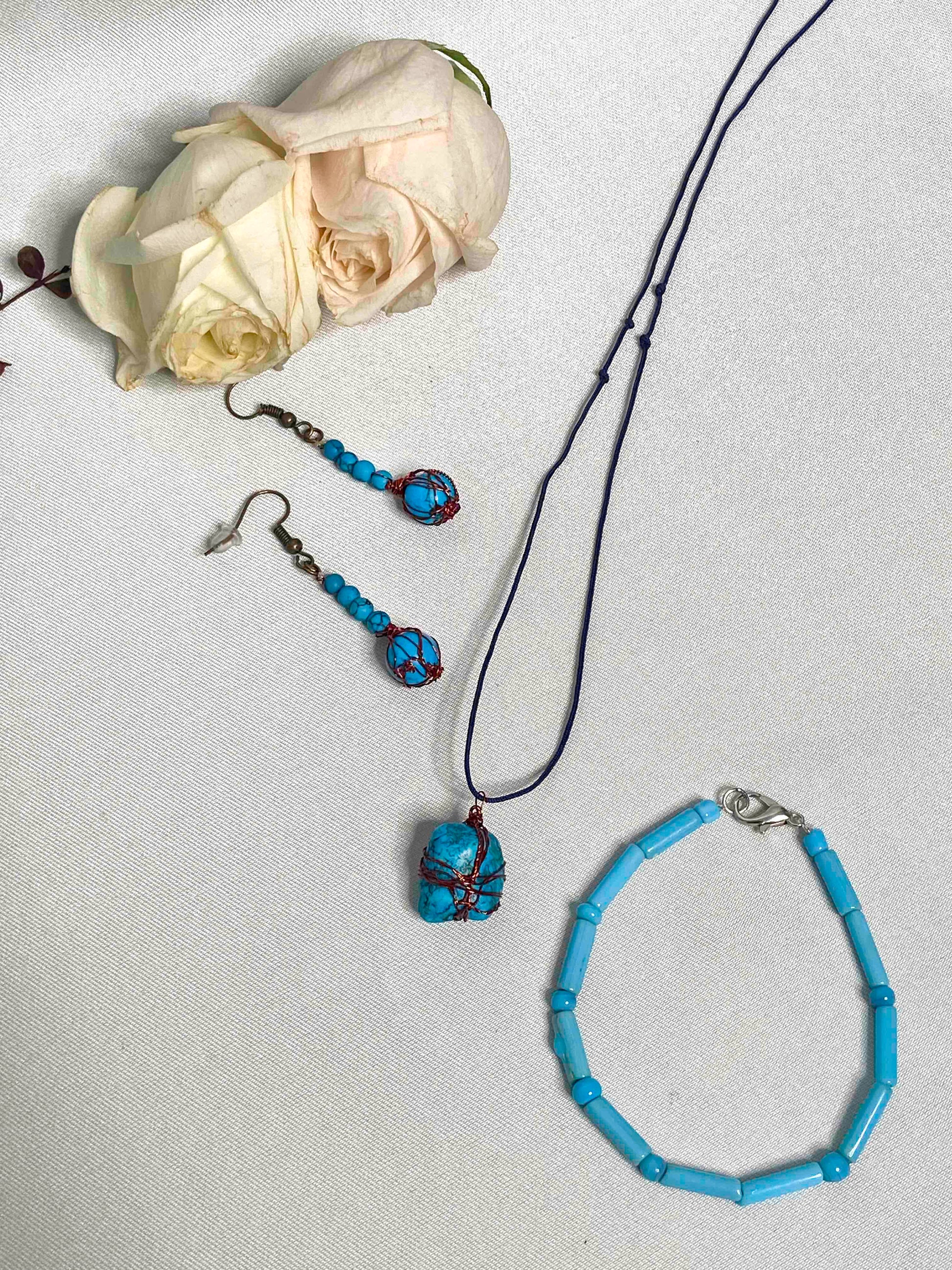A pair of handcrafted wire-wrapped and beaded turquoise earrings, a matching pendant necklace, and beaded bracelet.