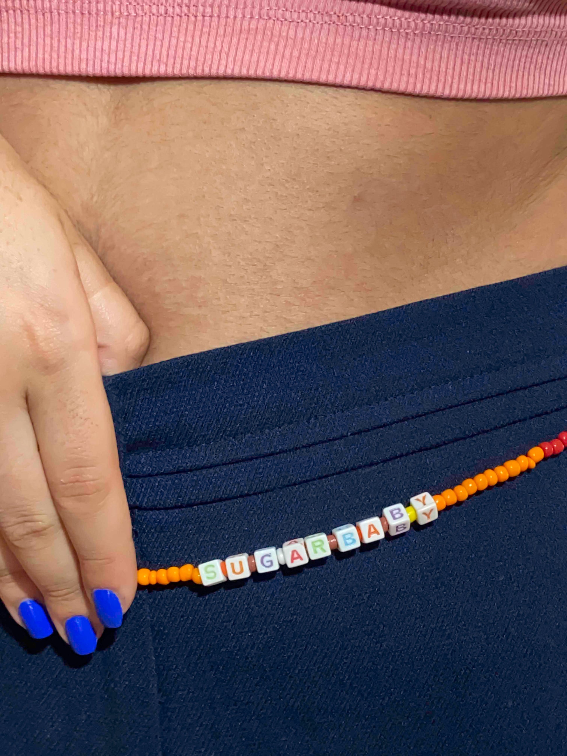 handcrafted orange, red, brown and white beaded belly chain with starfish charms and beaded letters.