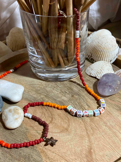 handcrafted orange, red, brown and white beaded belly chain with starfish charms and beaded letters.