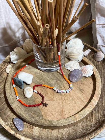 handcrafted orange, red, brown and white beaded belly chain with starfish charms and beaded letters.