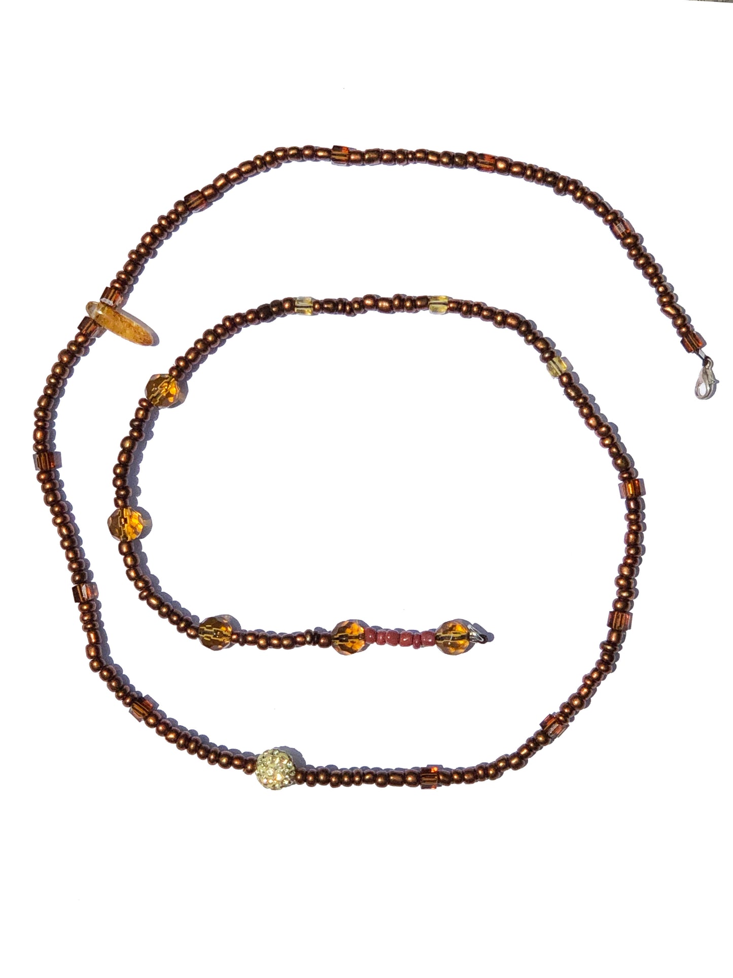 handcrafted belly chain beaded using a yellow tourmaline stone, yellow large glass beads, a crystal charm, and red and brown beads.