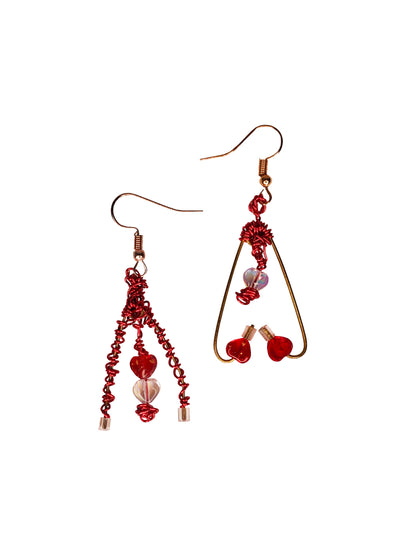 A pair of mismatched asymmetrical earrings wire wrapped using red and gold wires with clear & red heart beads, and a red crystal bead.