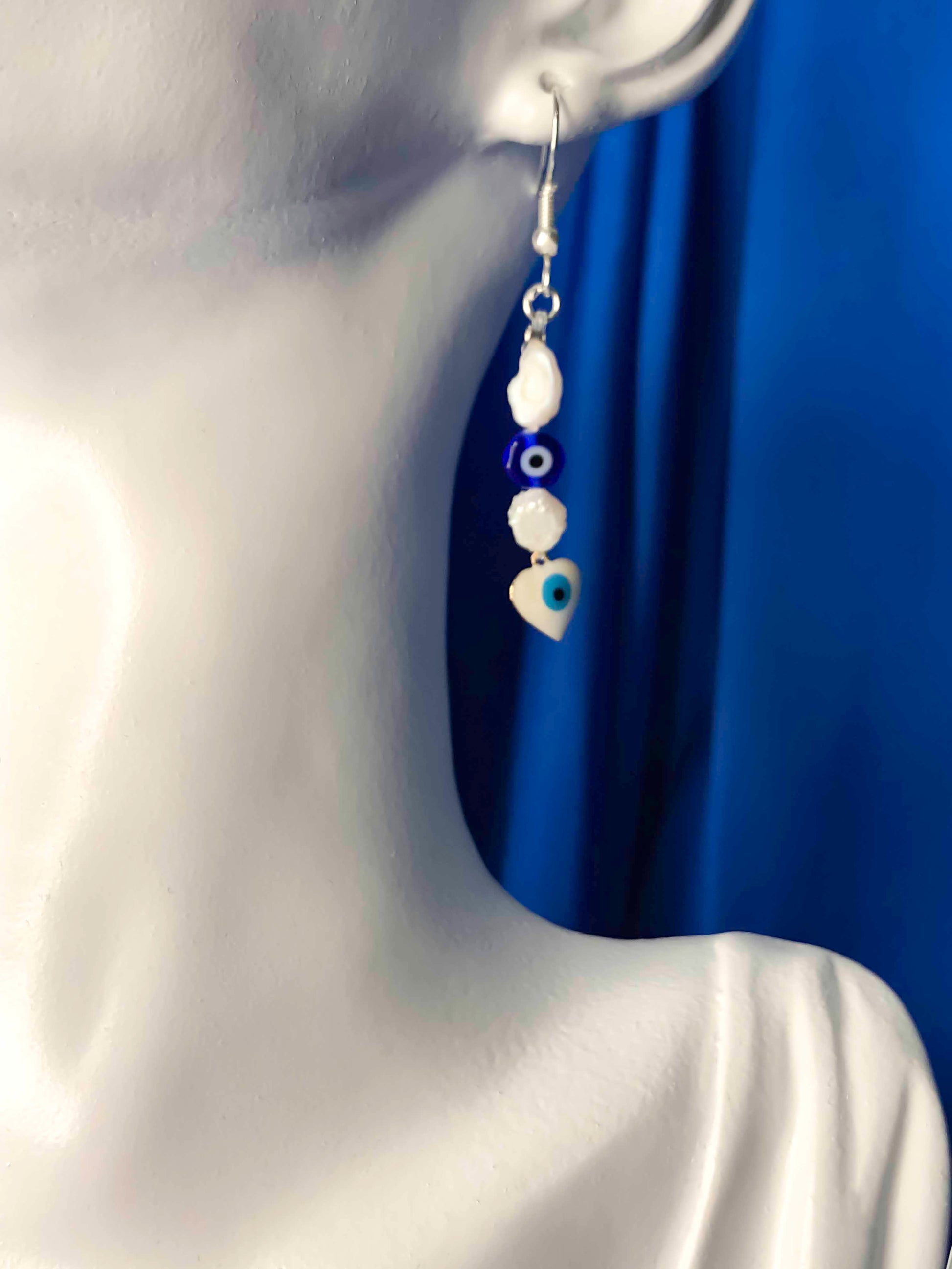 handmade freshwater pearl earrings with blue nazar amulet, and white evil eye charm.