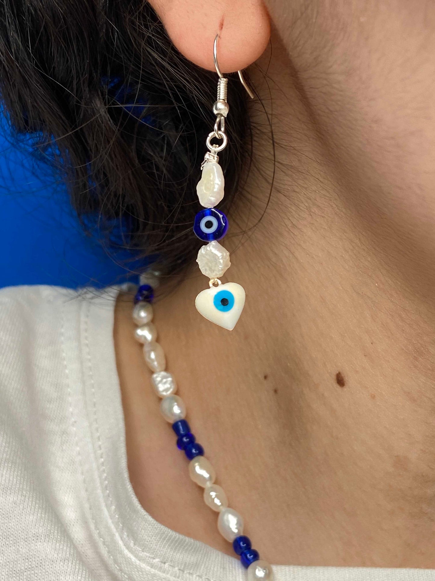 handmade freshwater pearl earrings with blue nazar amulet, and white evil eye charm.