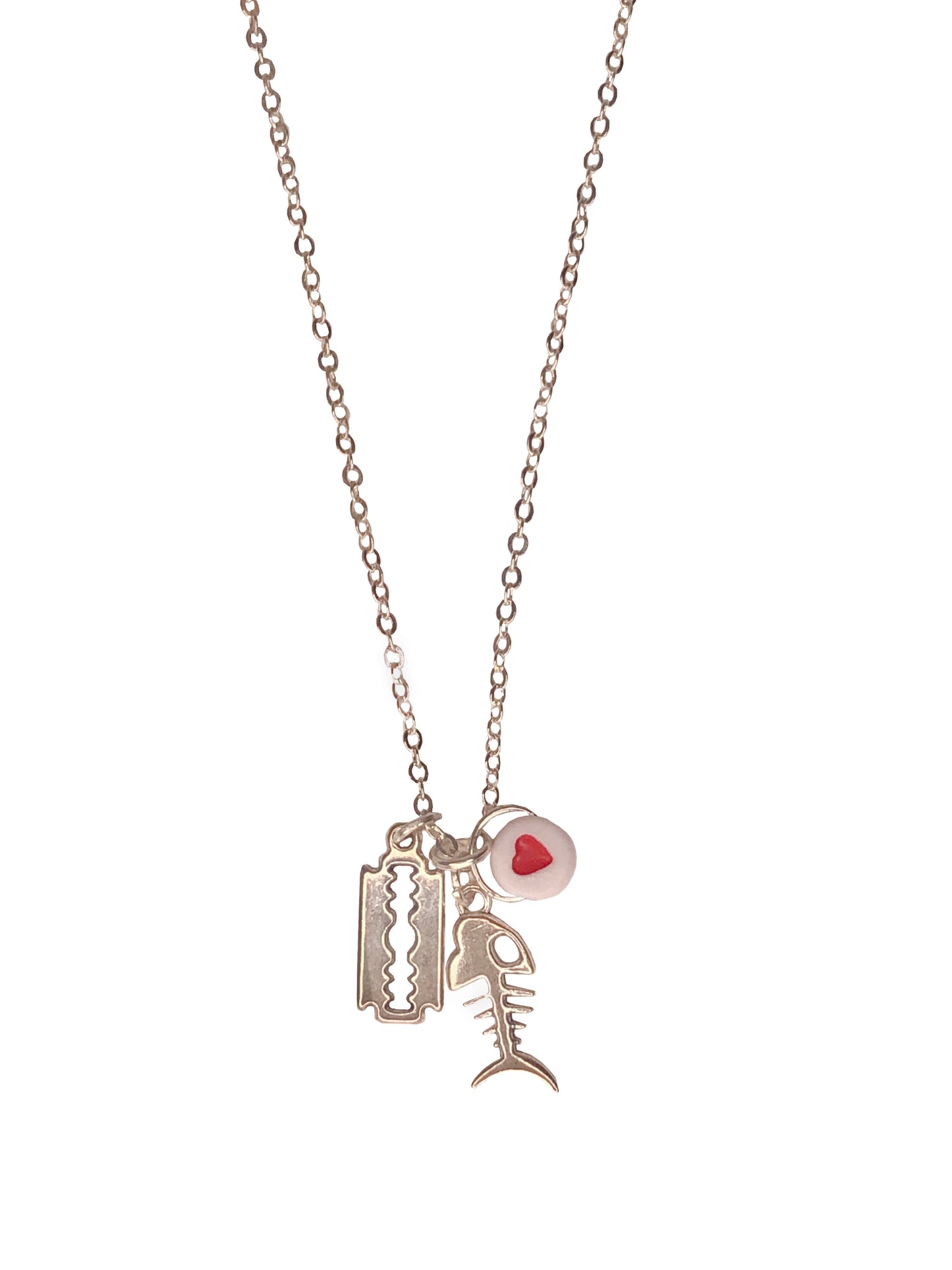 Handmade pendant necklace with a red flat round heart bead, a silver razor blade and skeleton fish charm.