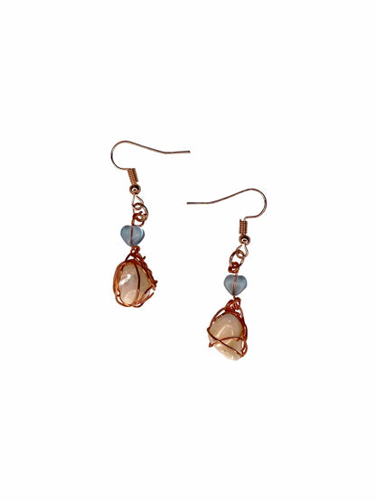 A pair of handmade copper wire wrapped freshwater pearl earrings.