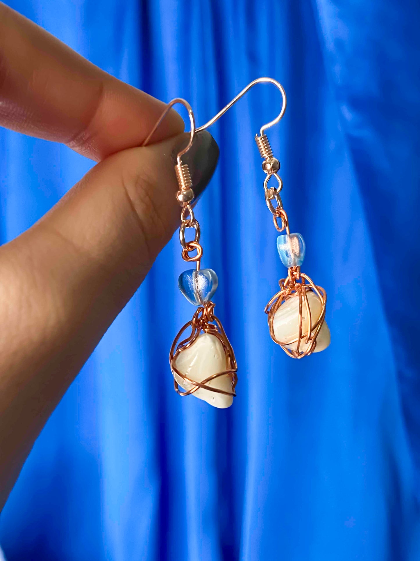 A pair of handmade copper wire wrapped freshwater pearl earrings.