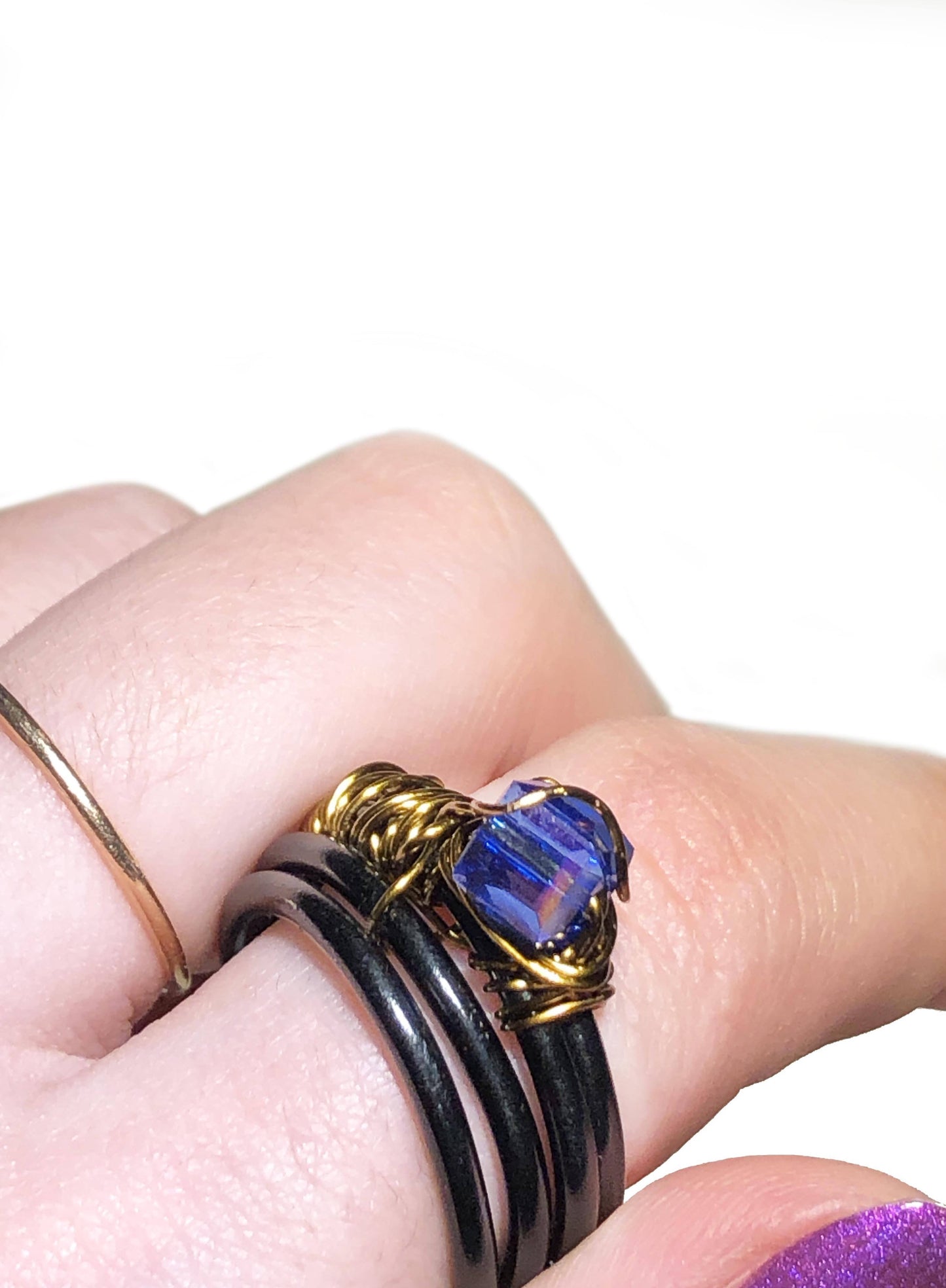 handcrafted ring made using a thick black wire wrapped base with a golden wire wrapped blue cube centerpiece.