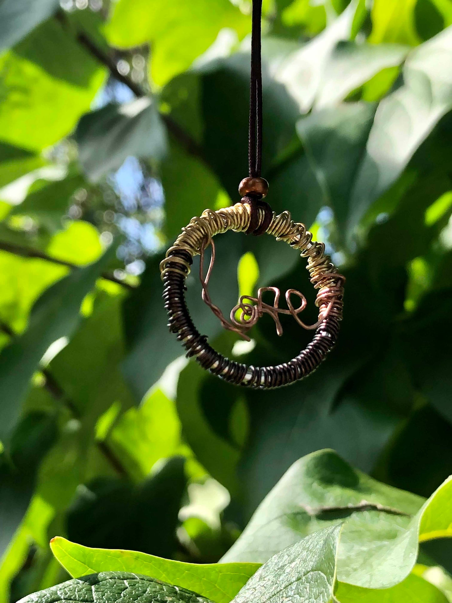 Golden and brown wire wrapped necklace with a copper wire that spells out love at the center, and a bronze bead on top