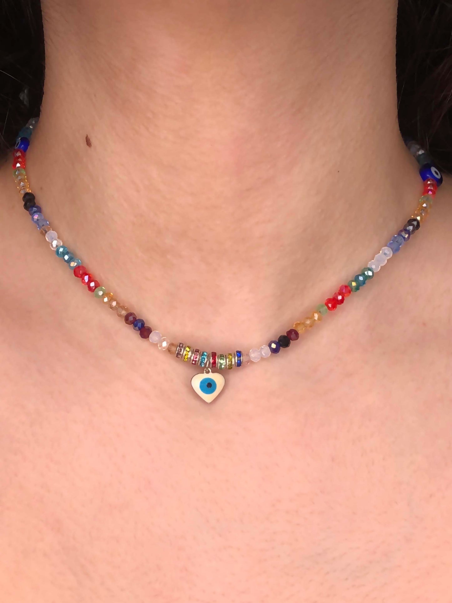 multicolored crystal beaded choker necklace with two circular blue evil eye charms, and a heart shaped evil eye pendant.